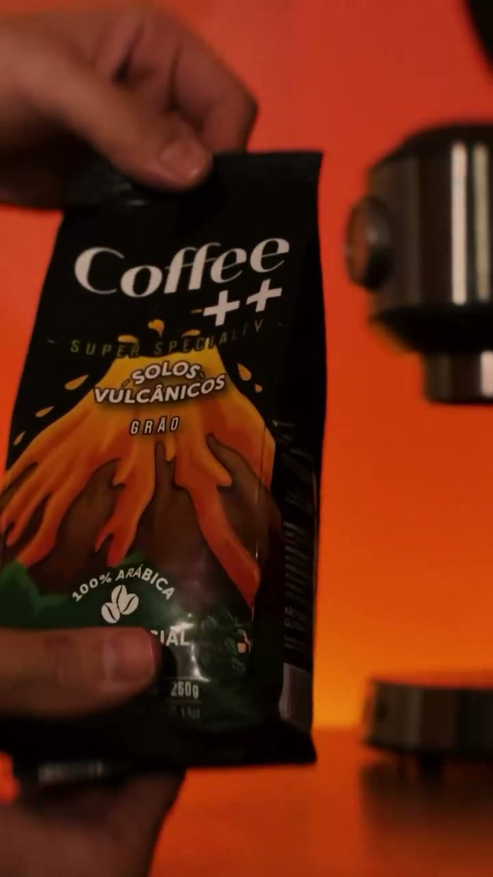 Pacote de café Coffee++ Solos Vulcânicos diante de uma máquina de espresso.